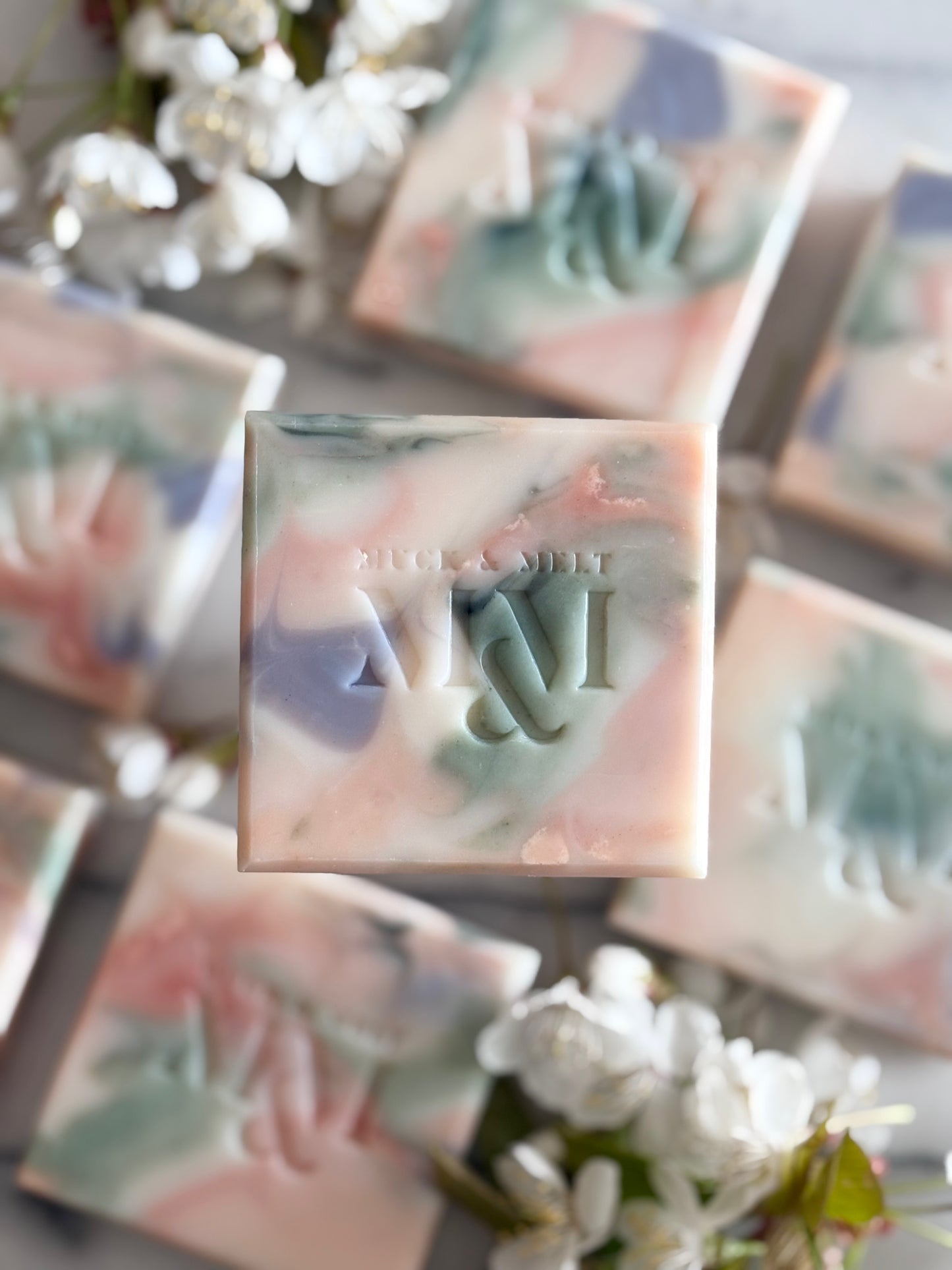 natural Artisan soap bar with floral-inspired swirls in natural pink, green, lilac and white hues with blossom flowers close up