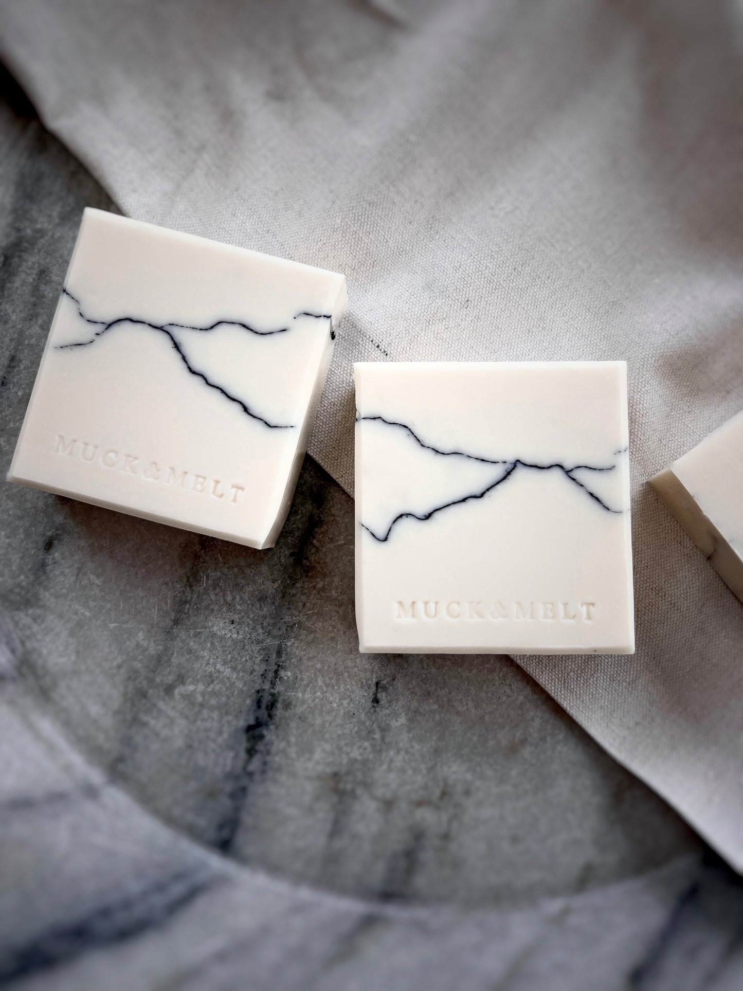 2 handmade soaps with black and grey strata patterns, inspired by rock formations