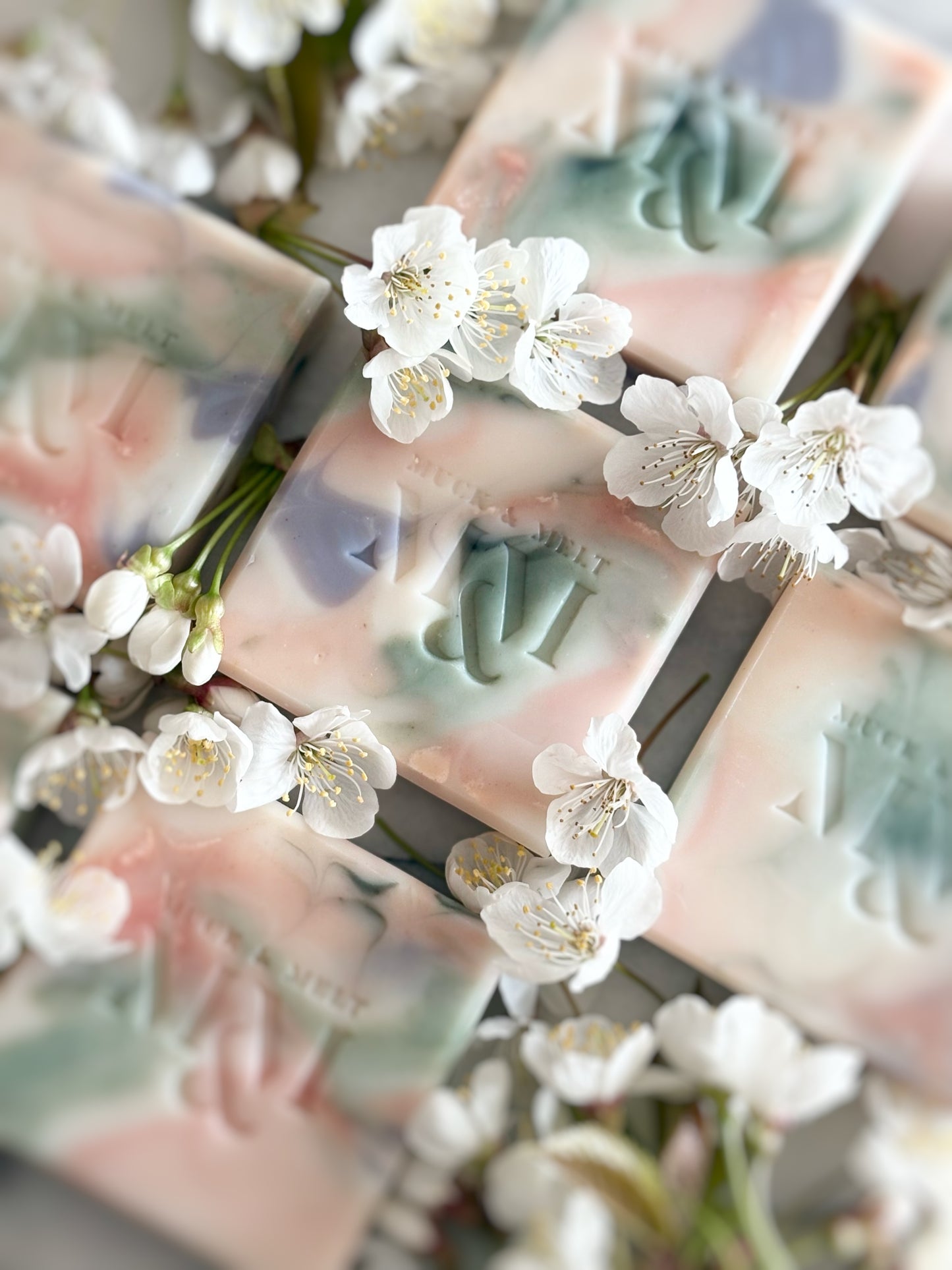 natural Artisan soap bar with floral-inspired swirls in natural pink, green, lilac and white hues with blossom flowers angled photo