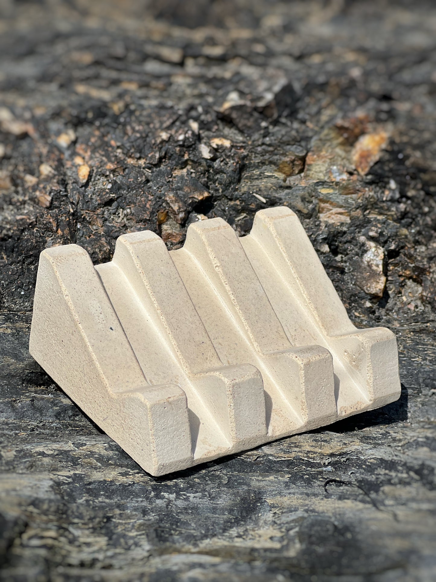 Handmade soap dish with sandy textures and natural stone-inspired finish pictured on rocks