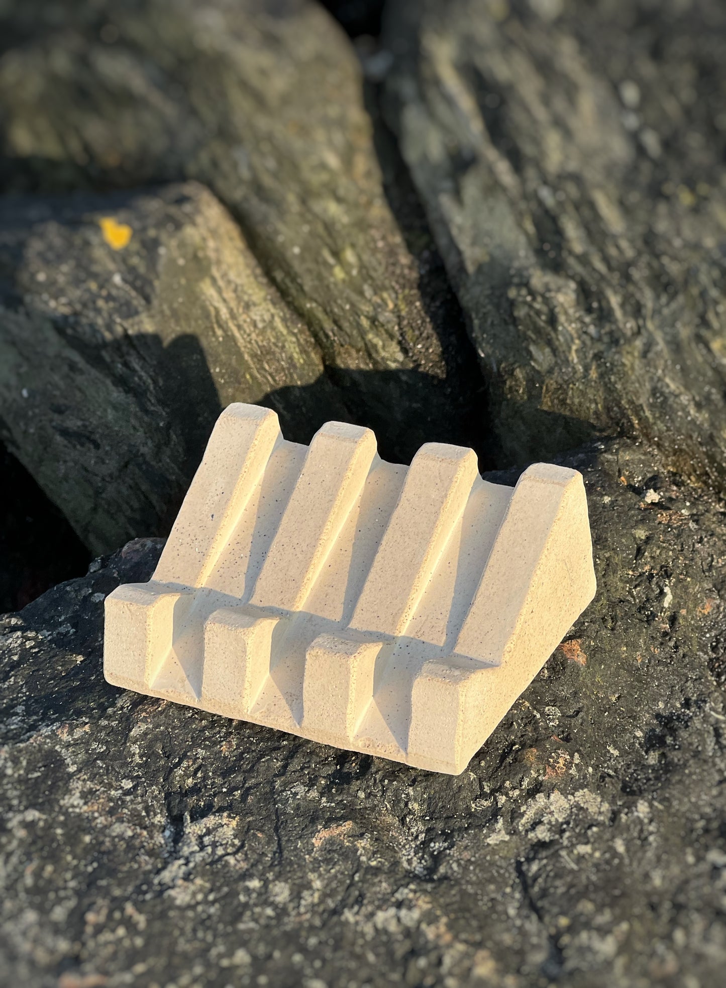 Handmade soap dish with sandy textures and natural stone-inspired finish on beach at sunset