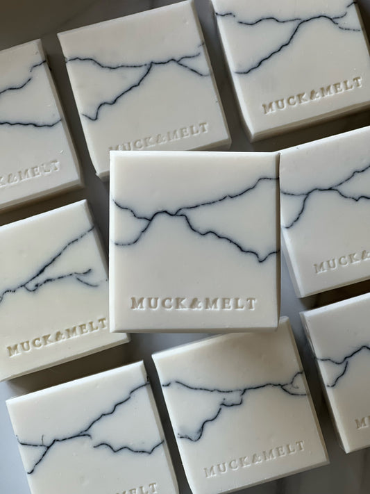 group of white marble handmade soap bars with black and grey strata patterns, inspired by rock formations