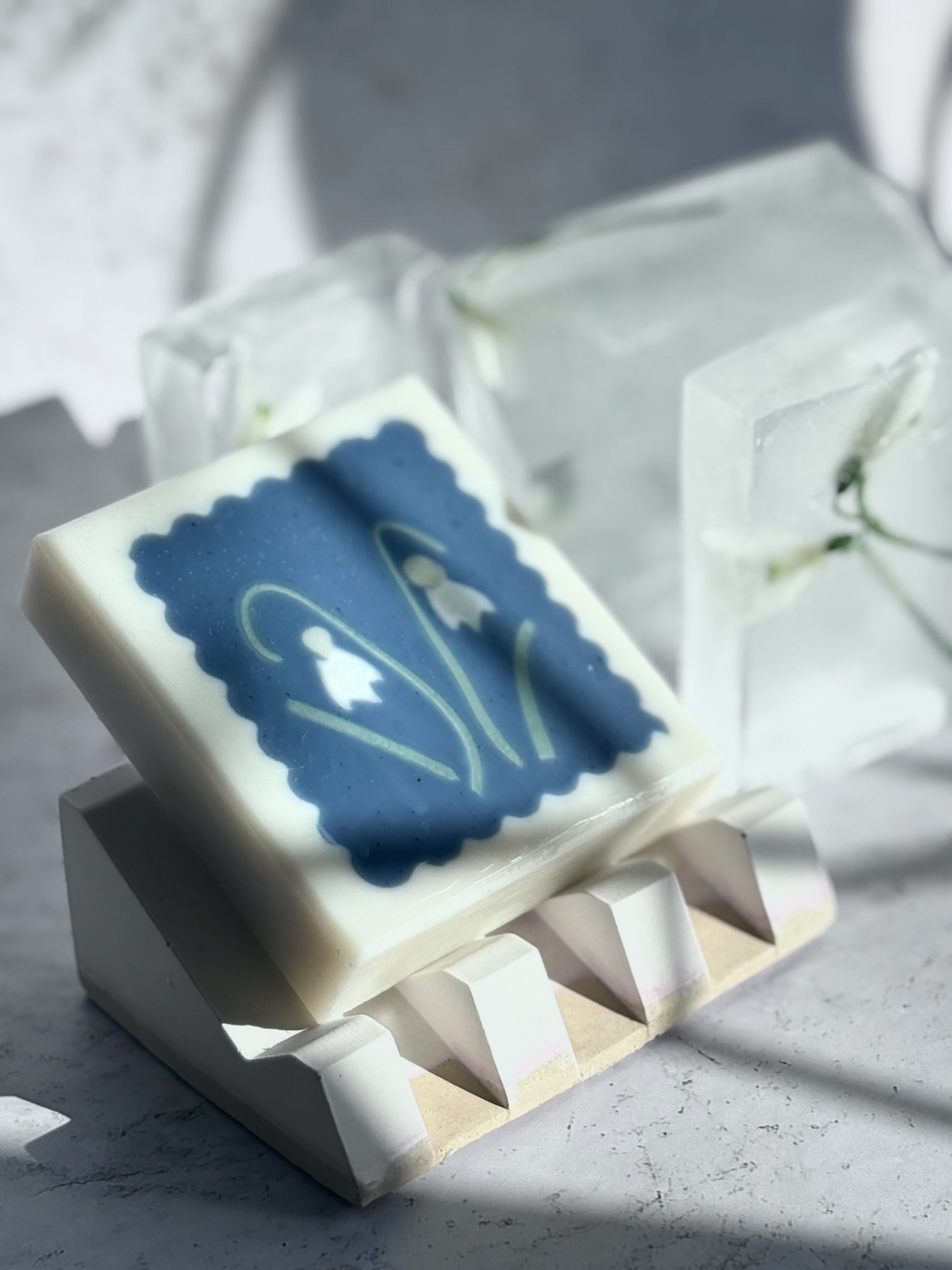 handmade artisan soap with snowdrop flower motifs on white soap dish and snowdrops preserved in ice
