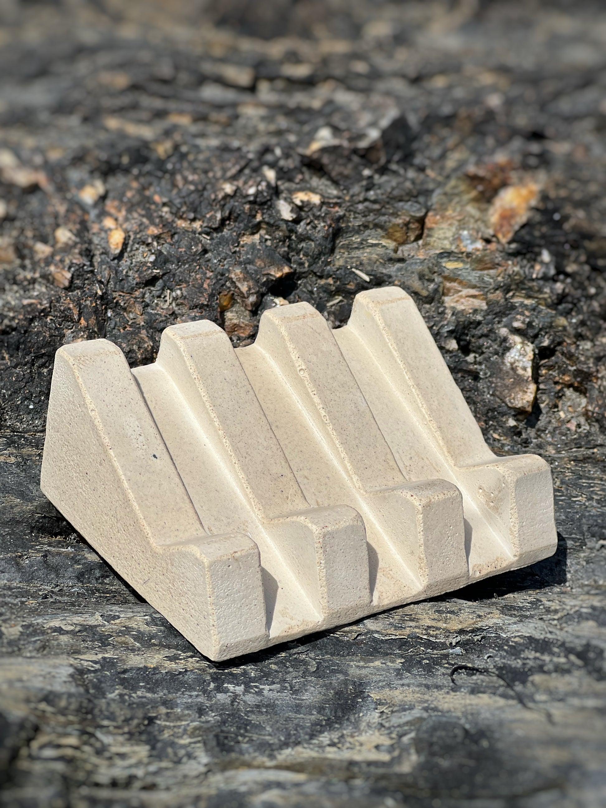 Handmade soap dish with sandy textures and natural stone-inspired finish pictured on rocks