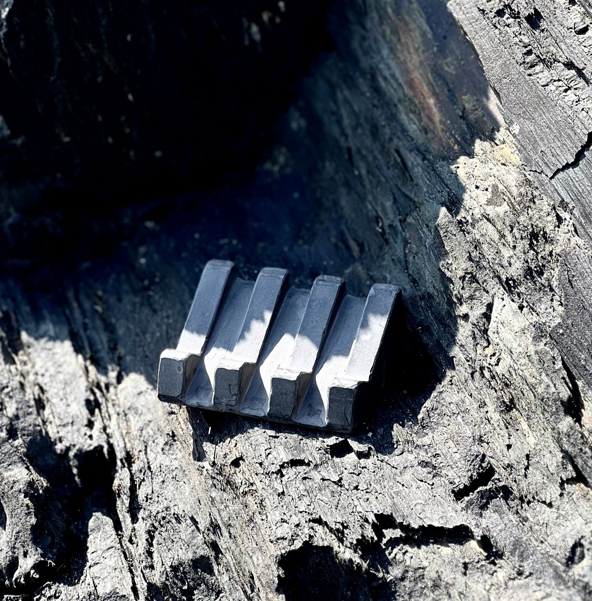 Black soap dish with organic design and slotted lines for drainage on rocks